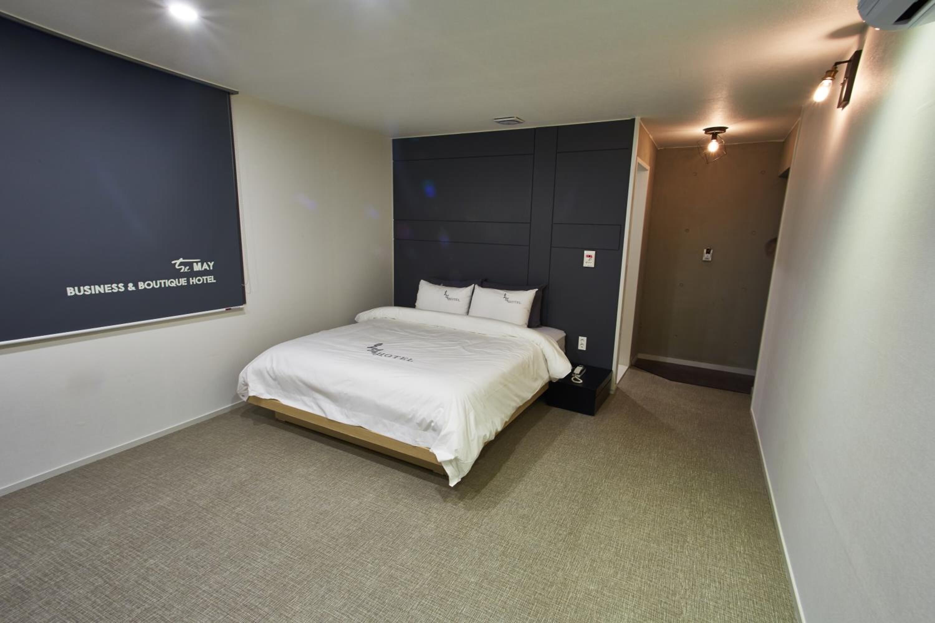Una habitación de hotel con una cama, una pared oscura con un logotipo y suelo alfombrado.