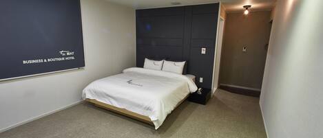 Una habitación de hotel con una cama, una pared oscura con un logotipo y suelo alfombrado.