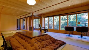 A modern interior with a large window, a cushioned seating area, and a table. - Tatsuta Ryokan (Izu)
