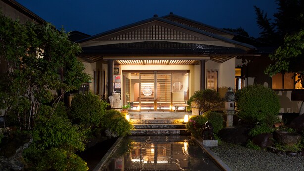 A traditional Japanese building with a stone water feature in front. - Tatsuta Ryokan (Izu)