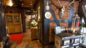A rustic interior with exposed brick walls, a wooden cabinet, a vintage stove, and antler decorations. - Hotel Alter Wolf (Wolfsburg)