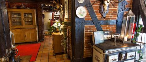 A rustic interior with exposed brick walls, a wooden cabinet, a vintage stove, and antler decorations.