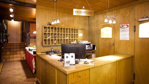A reception desk with a wooden finish, a computer, and a bulletin board. - Hotel Alter Wolf (Wolfsburg)