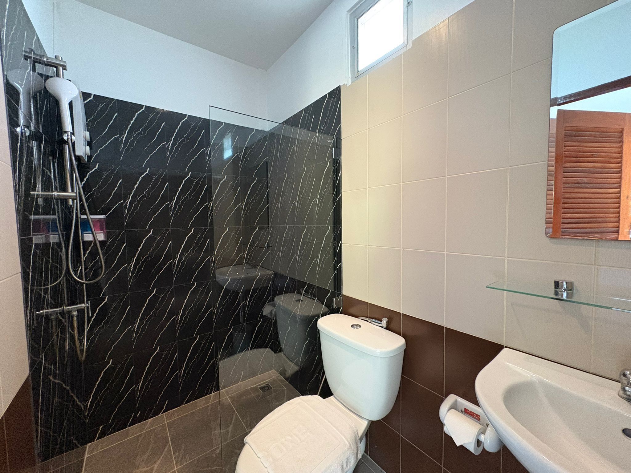A bathroom with a glass shower enclosure, a toilet, and a sink.