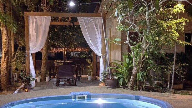 A swimming pool with a wooden deck, potted plants, and a covered seating area. - Canal Resort (Sa Khu)