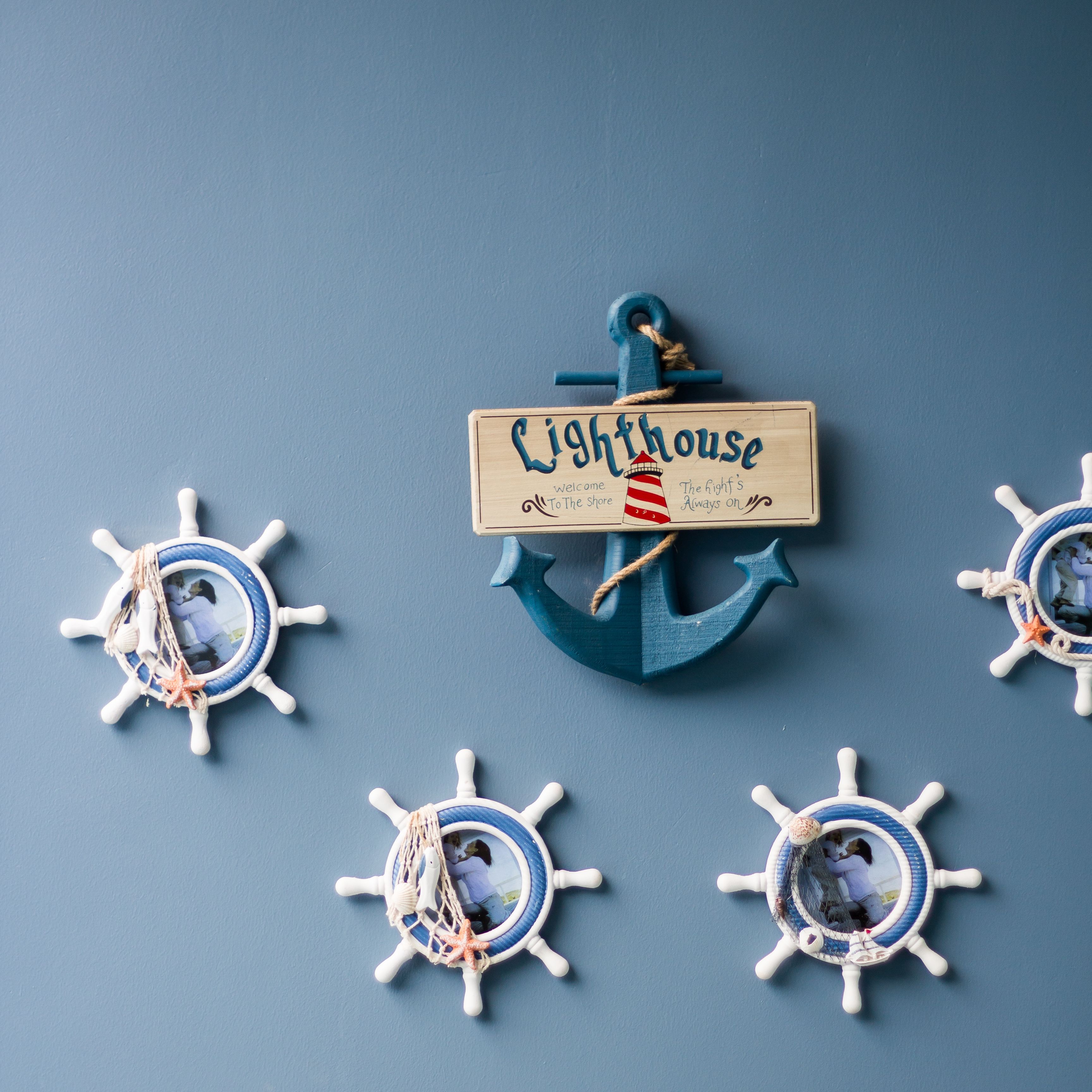 A nautical-themed decoration with a wooden sign reading "Lighthouse" and four ship's wheel ornaments.