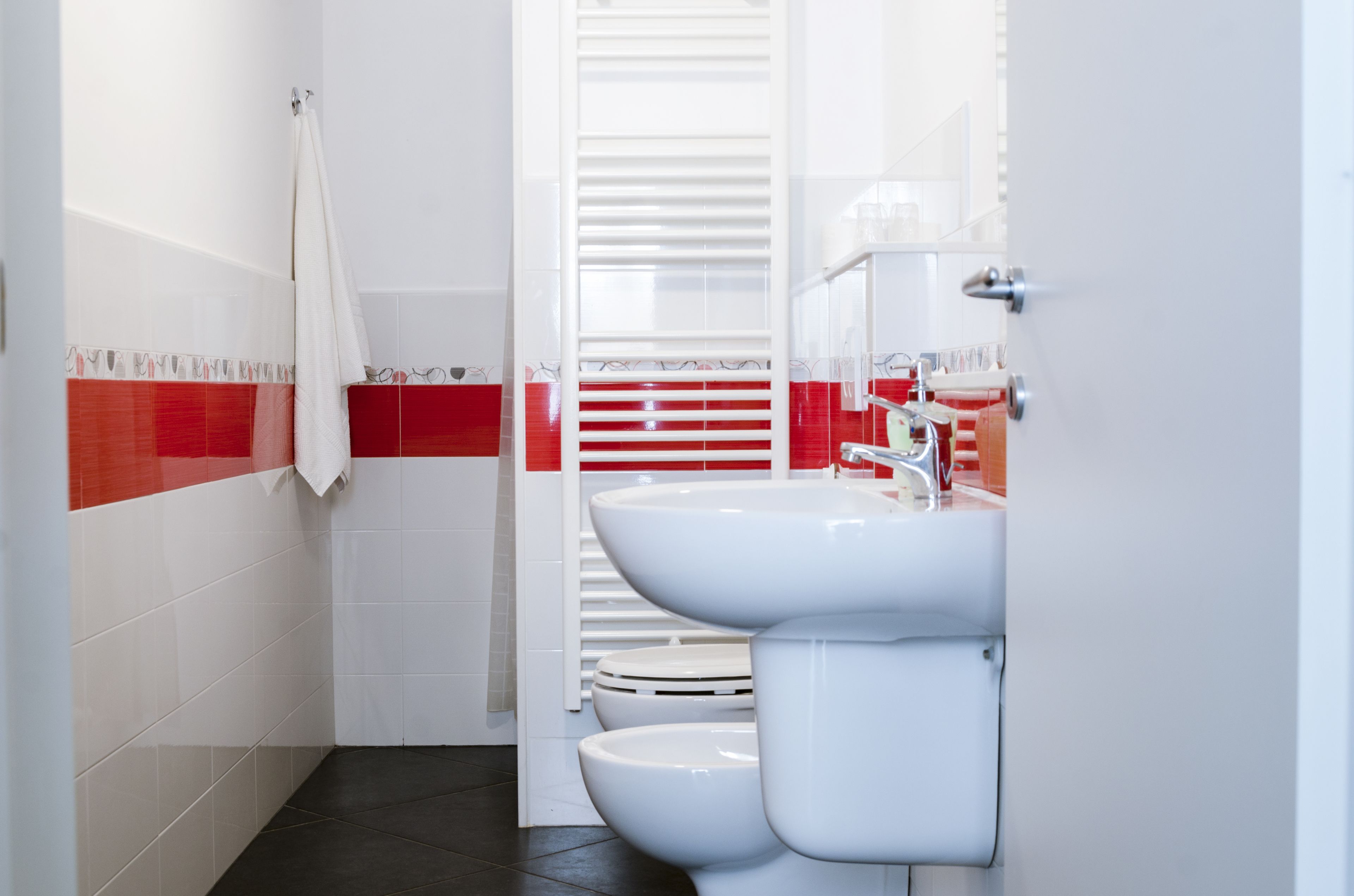A bathroom with white and red tiled walls, a white sink, and a toilet.