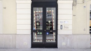 A black double door with a glass panel, a sign for 'Maria Vittoria', and a small window with a red frame.
