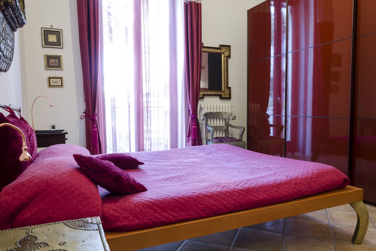 Een kamer met een bed, een stoel, een radiator en een spiegel aan de muur.