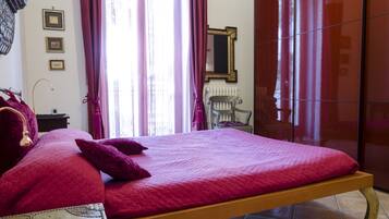 Una habitación con una cama, una silla, un radiador y un espejo en la pared.