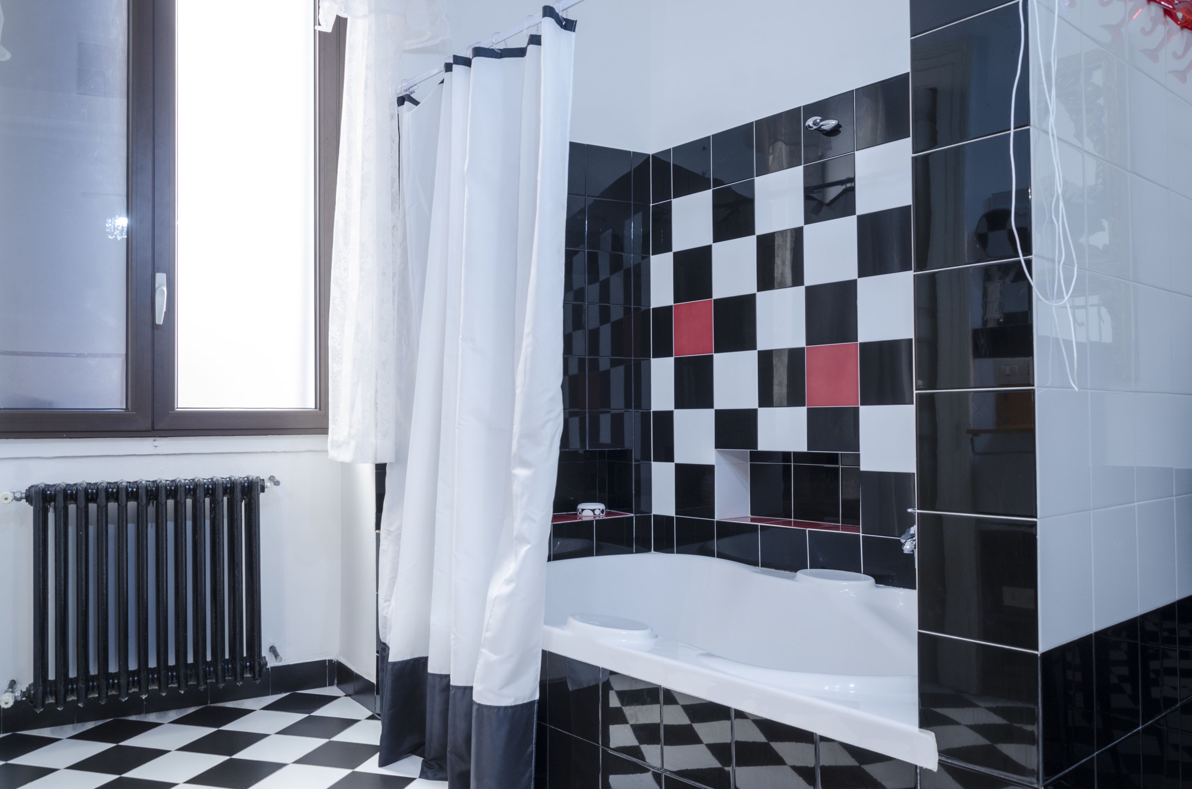 A bathroom with a checkered floor, a bathtub, and a shower area with a curtain.