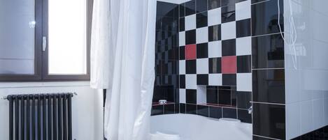 A bathroom with a checkered floor, a bathtub, and a shower area with a curtain.