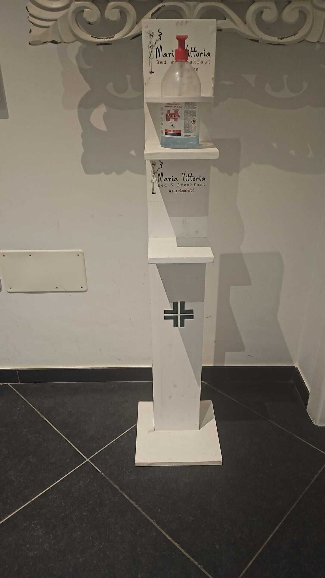 A white display stand with a logo and text for Maria Vittoria Bed & Breakfast Apartments.