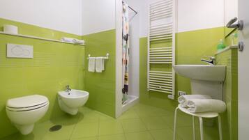 Un baño con inodoro, bidé y lavamanos, con azulejos verdes y sanitarios blancos.