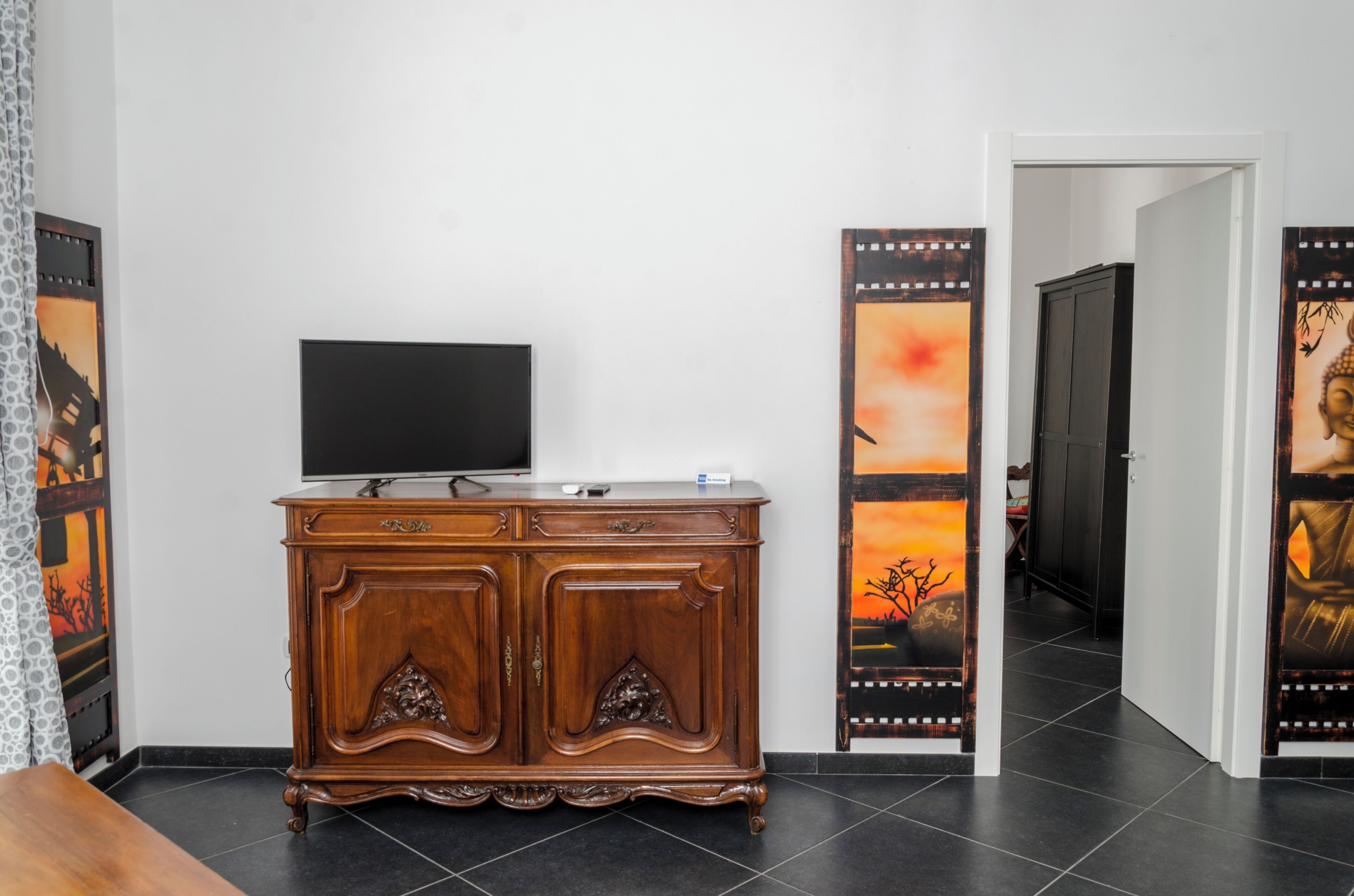 A room with a wooden cabinet, a flat-screen TV, and two decorative panels on the walls.