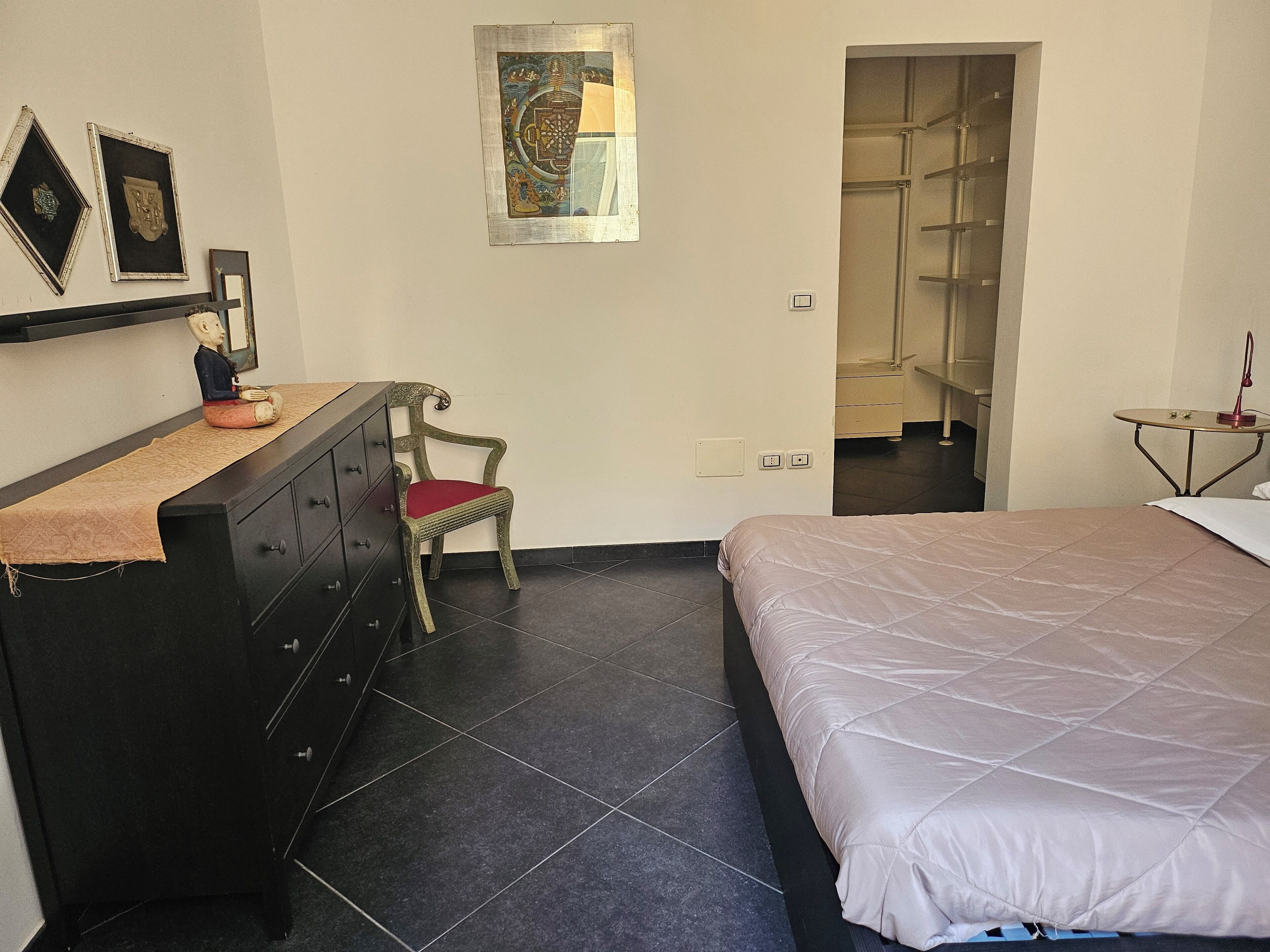 A bedroom with a bed, a dresser, a chair, and a small table.