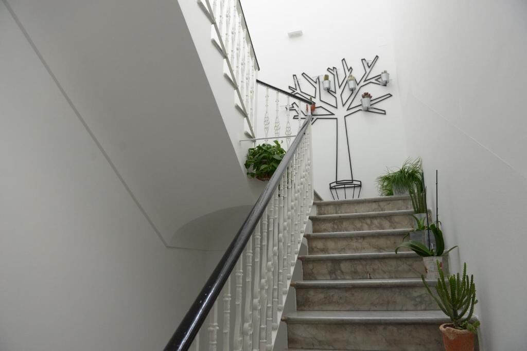 A staircase with a white railing, potted plants, and a wall-mounted abstract art piece.