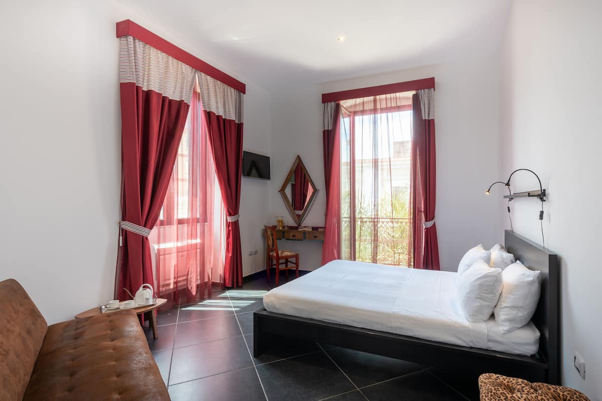 Een slaapkamer met een bed, een bank, een bureau en een stoel.
