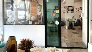 A hotel lobby with a modern design, featuring a glass door, a seating area with a blue sofa, and a small table with amenities. - Sleep Sheep Phuket Hostel SHA (Phuket)