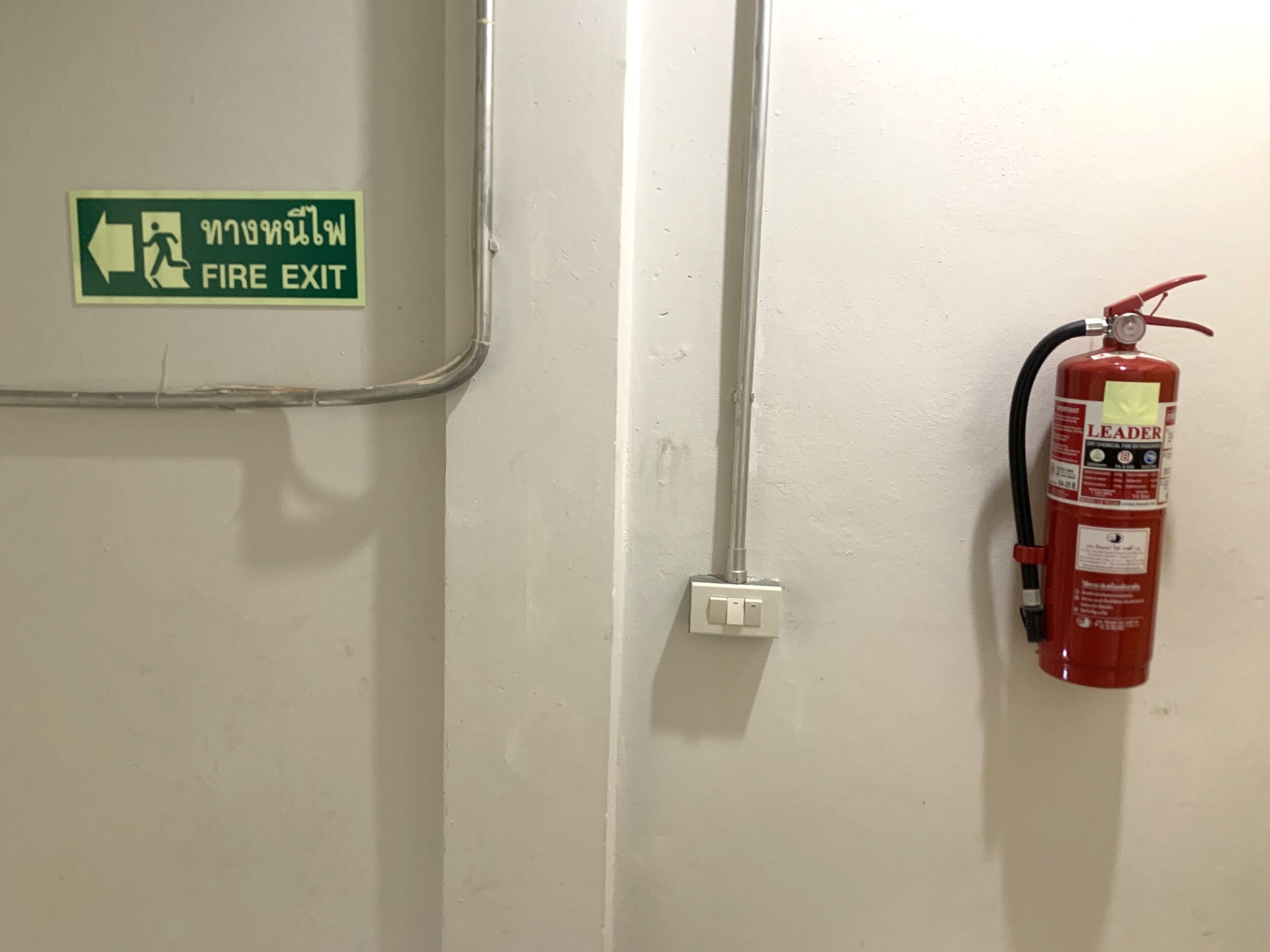 A fire exit sign and a fire extinguisher mounted on a wall.