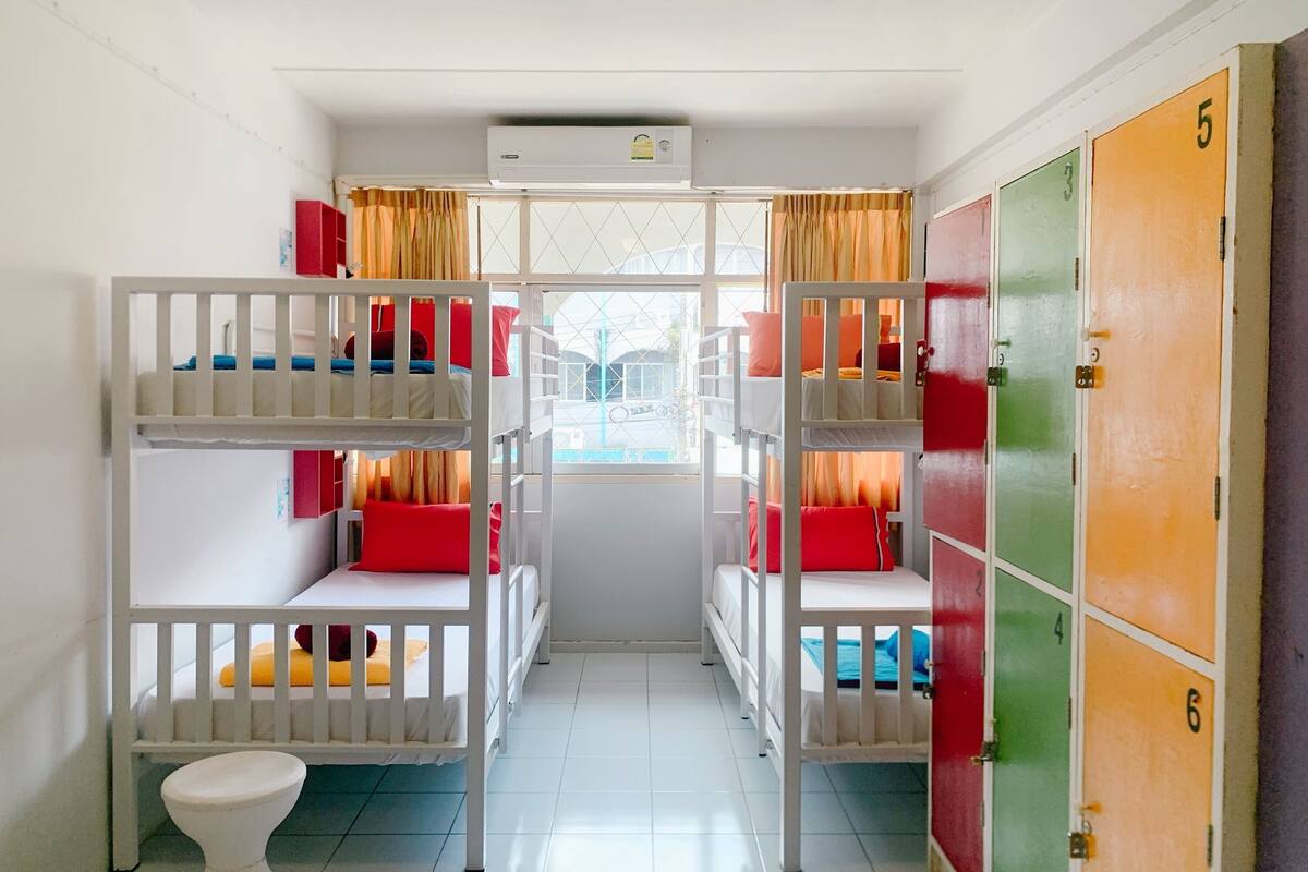 A dormitory room with bunk beds, a toilet, and colorful lockers.
