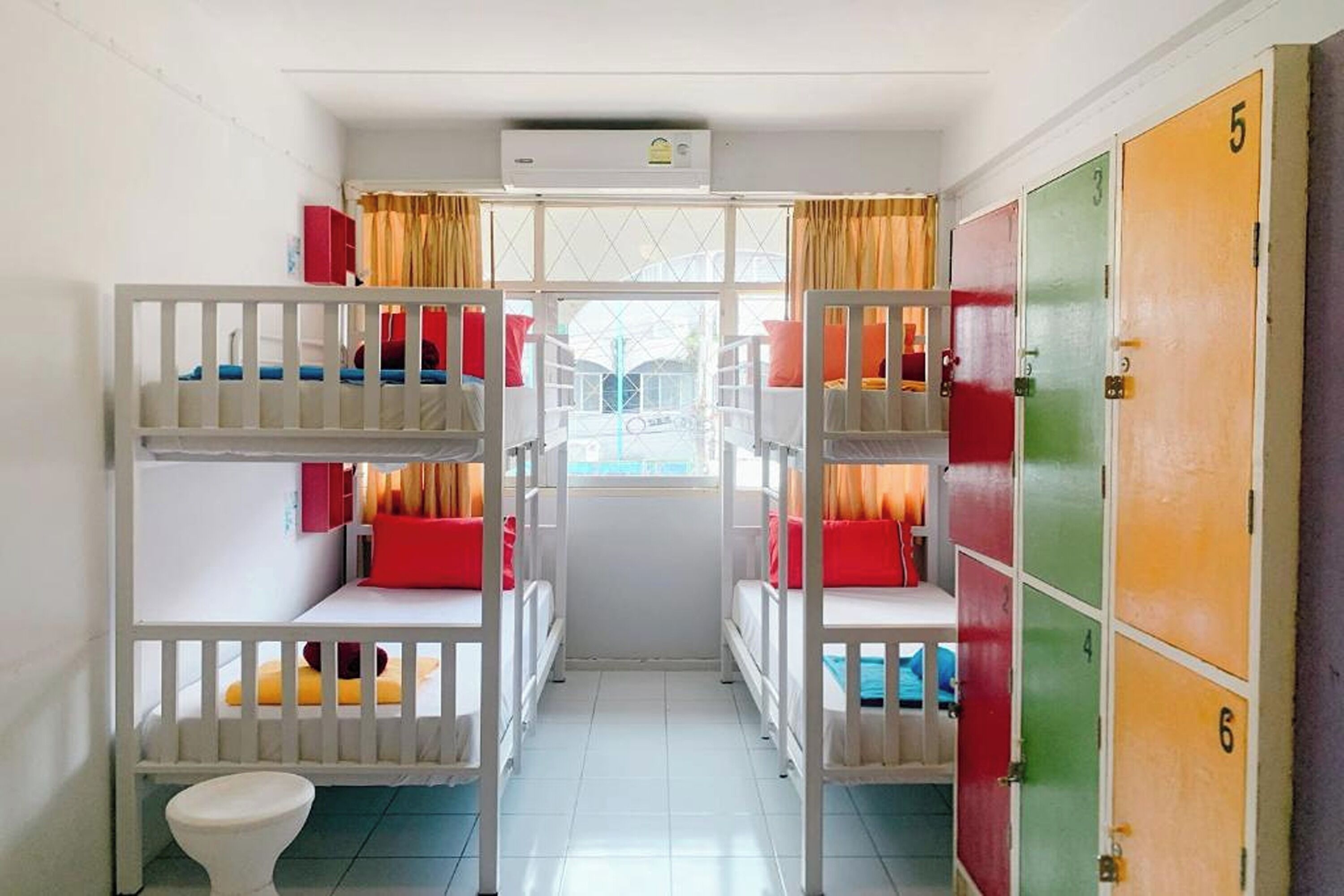 A dormitory room with bunk beds, a toilet, and lockers.