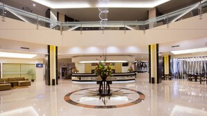 A spacious lobby with a central floral arrangement, a reception desk, and a seating area with sofas.