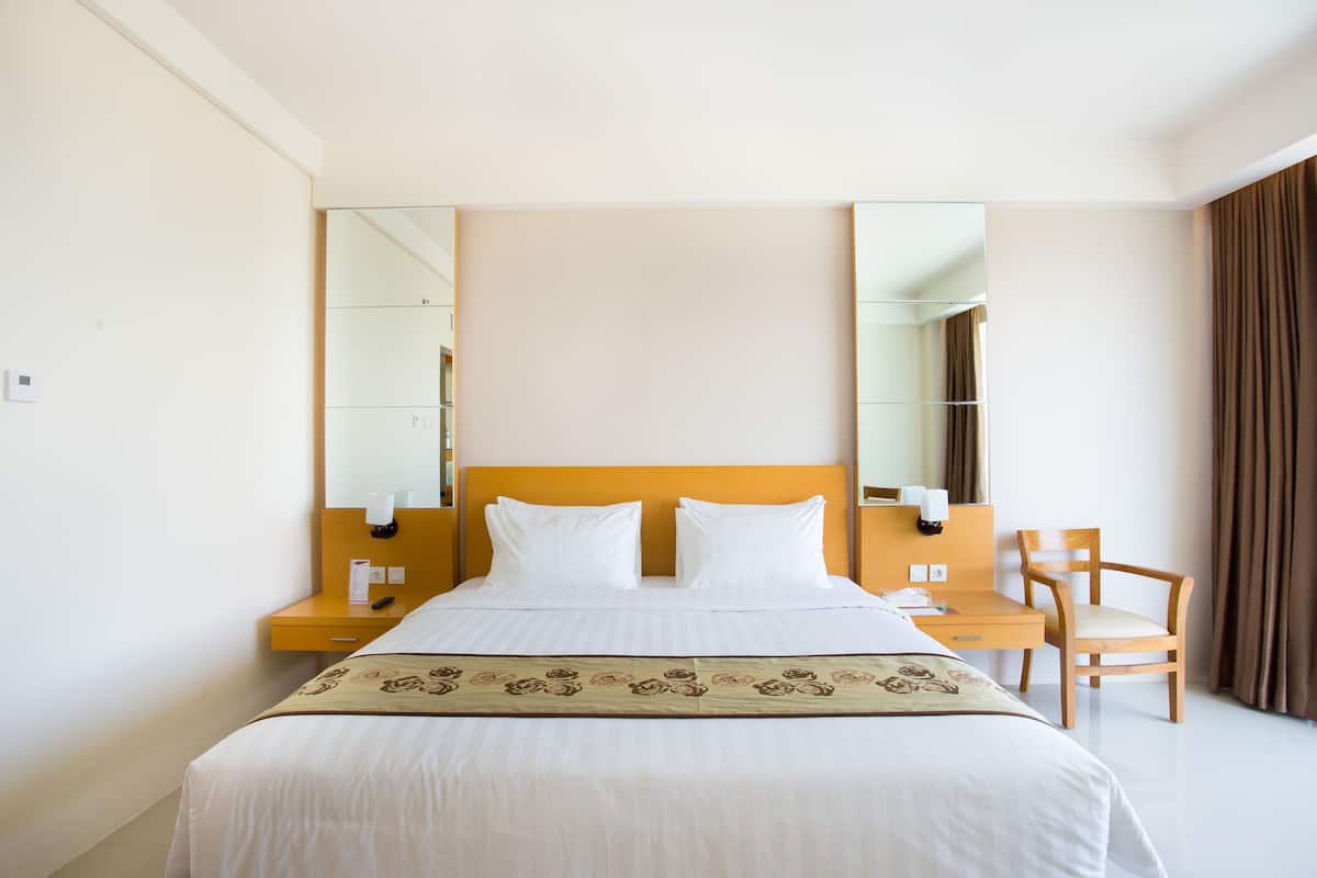 Una habitación de hotel con cama, escritorio, silla y un espejo grande.