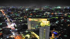 A hotel with a prominent sign, multiple floors, and a parking area.