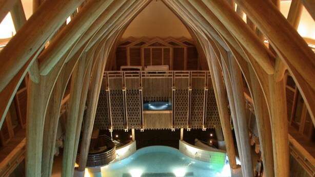 An indoor hot tub area with wooden beams and a seating area. - Hôtel La Mandia (Bagnères-de-Bigorre)