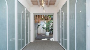 A hallway with sliding glass doors, a wooden ceiling, and a potted plant. - Hotel Aristoy-by Grupo Tribu (Tarifa)