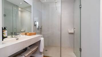Un baño moderno con cabina de ducha de vidrio, un espejo grande y un tocador con toallero.