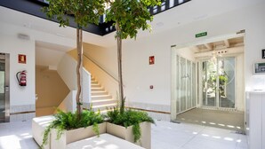 A modern lobby with a staircase, a fire extinguisher, a glass door, and a sign indicating the exit. - Hotel Aristoy-by Grupo Tribu (Tarifa)