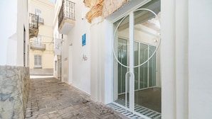 A narrow alleyway with stone paving leading to a building entrance with a glass door and a metal railing. - Hotel Aristoy-by Grupo Tribu (Tarifa)