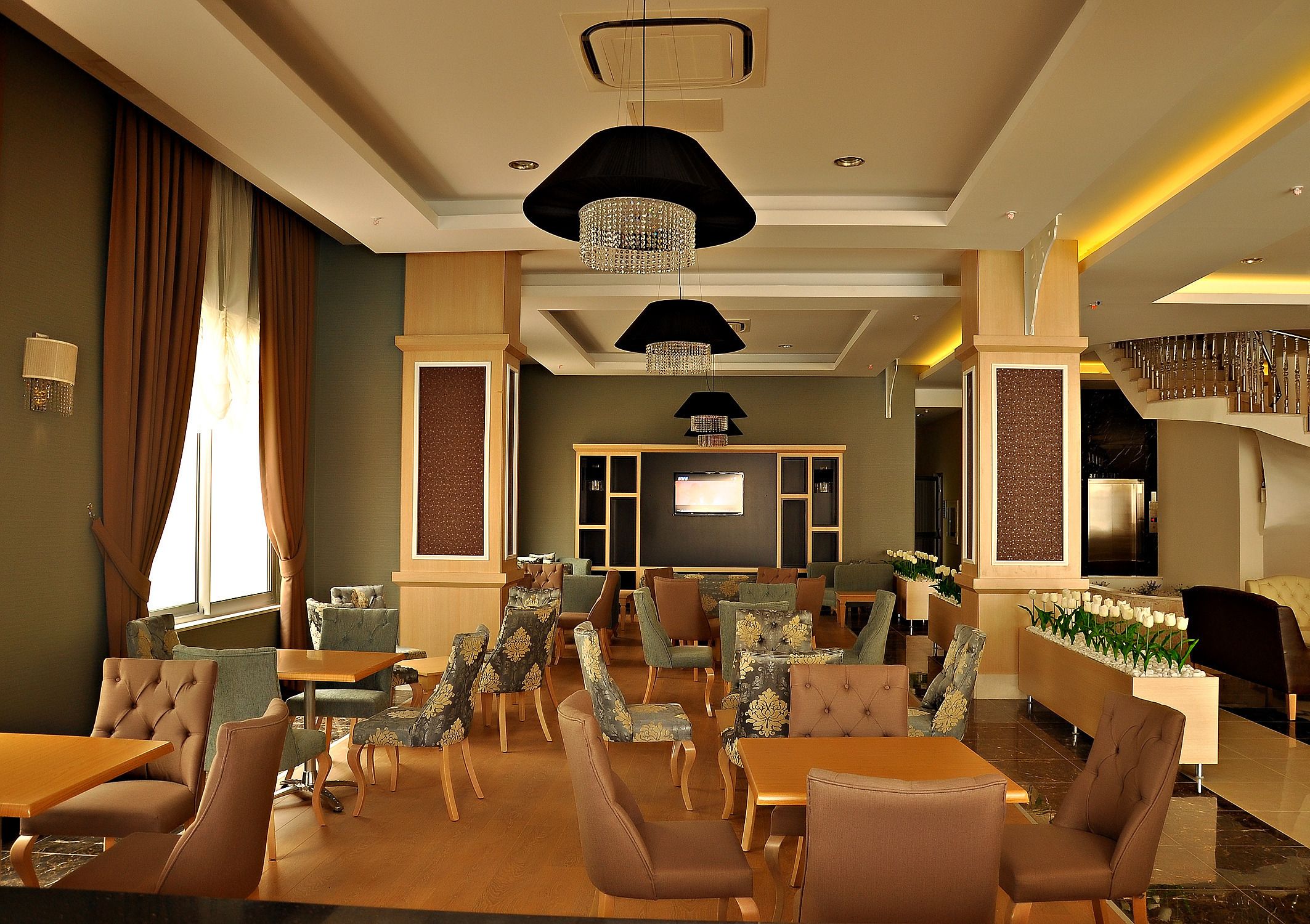 A hotel lobby with a modern design, featuring a variety of seating arrangements, a reception desk, and a large screen.