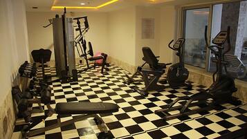 Une salle de sport avec un sol à carreaux, divers appareils d’exercice et une fenêtre donnant sur l’extérieur.