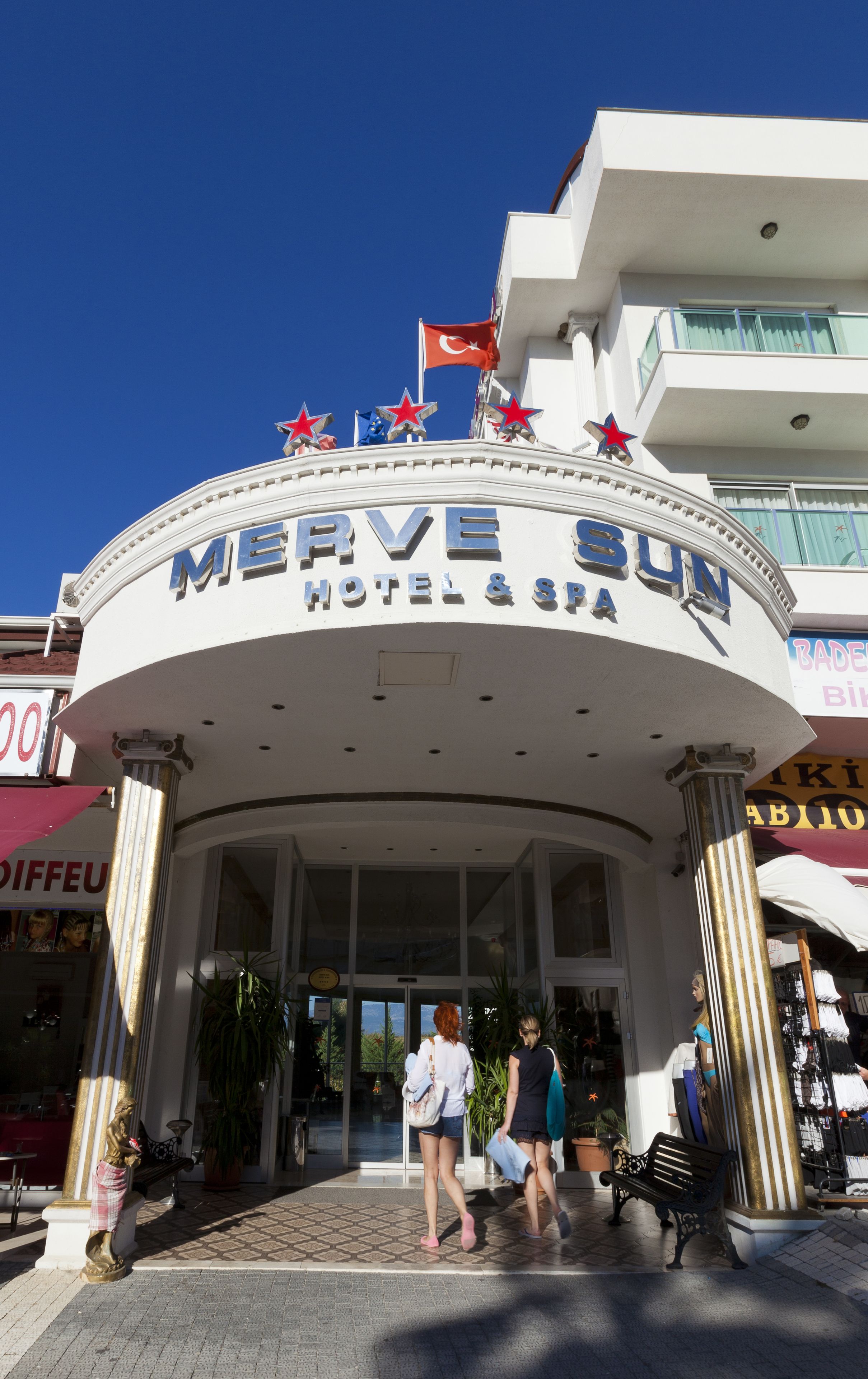 Exterior del Merve Sun Hotel & Spa con una entrada despejada, una bandera y una decoración con estrella en la parte superior.