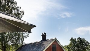 A red barn with a gabled roof, a chimney, and a white door. - Swedish Idyll (Falkenberg)