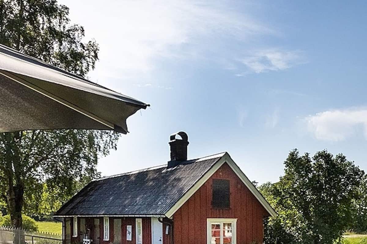 A red barn with a gabled roof, a chimney, and a white door.