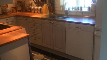 Una cocina con armarios blancos, un lavamanos y una ventana con cortinas.