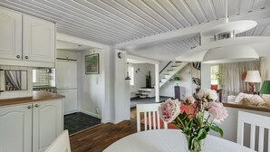 A spacious living area with a dining table, white furniture, and a staircase leading to another level. - Swedish Idyll (Falkenberg)