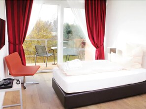 Un dormitorio con cama, una silla y un balcón con asientos.