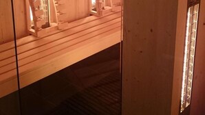 Una sala de sauna con paredes y bancos de madera, una puerta de cristal y techo rojo.