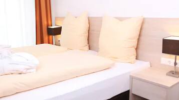 Quarto de hotel com cama, almofadas, mesa de cabeceira e luminária.
