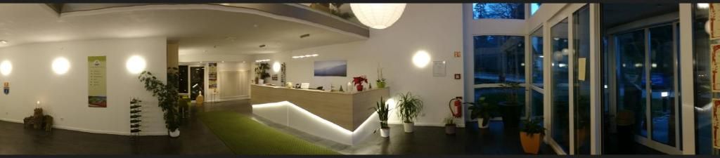 Un espace d’accueil avec un comptoir, des plantes en pot et une vue sur l’extérieur.