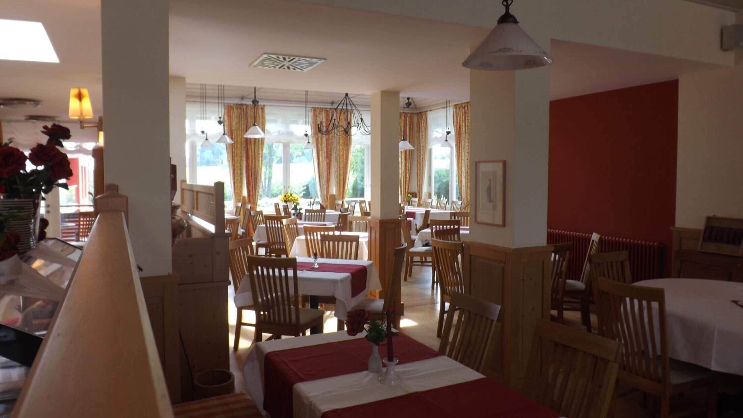 Ein Restaurant mit Holztischen, mehreren Sitzplätzen und einer Wand in Rot.