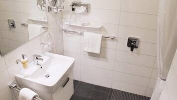 Un baño con lavamanos, espejo, toallero y soporte para papel higiénico.