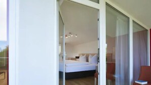 Un dormitorio con una cama, una silla y un ventanal de vidrio que da a un espacio exterior.