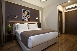Un dormitorio moderno con una cama grande, lámparas de noche, un cuadro en la pared y suelo de madera.