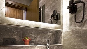 A bathroom with a large white sink, a mirror, a towel rack, and a potted plant. - SNOG Rooms & Suites (Istanbul)